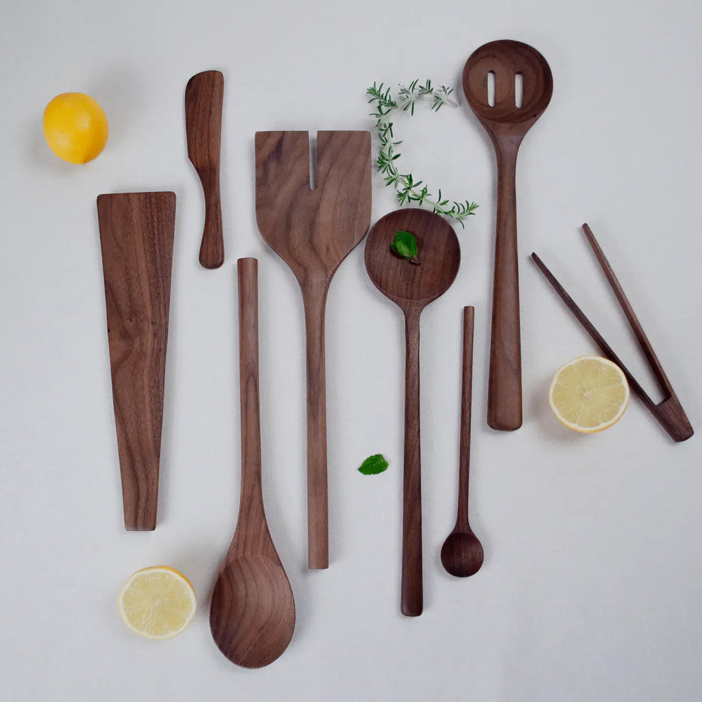 Set of wooden kitchen utensils on a light background with lemons and herbs.