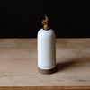 White ceramic oil bottle with gold cap on a wooden surface