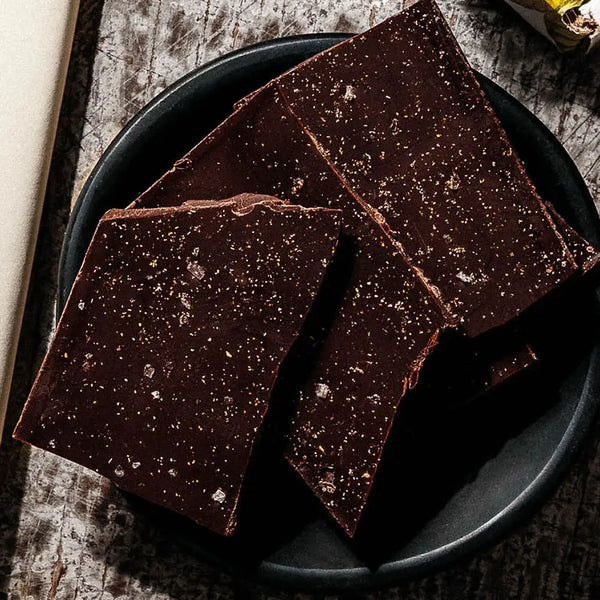 Dark chocolate bars on a black plate with a rustic wooden background