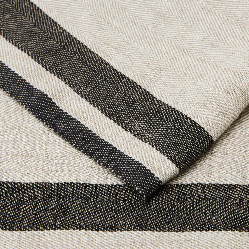 A close-up of a woven textile with a cream base and bold black horizontal stripes, showing the fabric texture and fold detail.