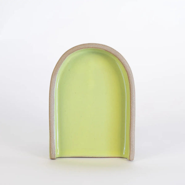 Ceramic arch-shaped object with a green interior on a white background
