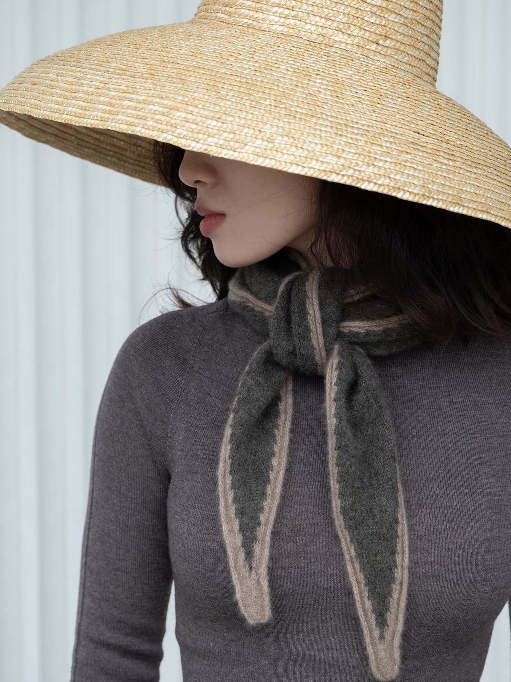 Woman wearing a wide brimmed hat wearing a green and beige cashmere scarf