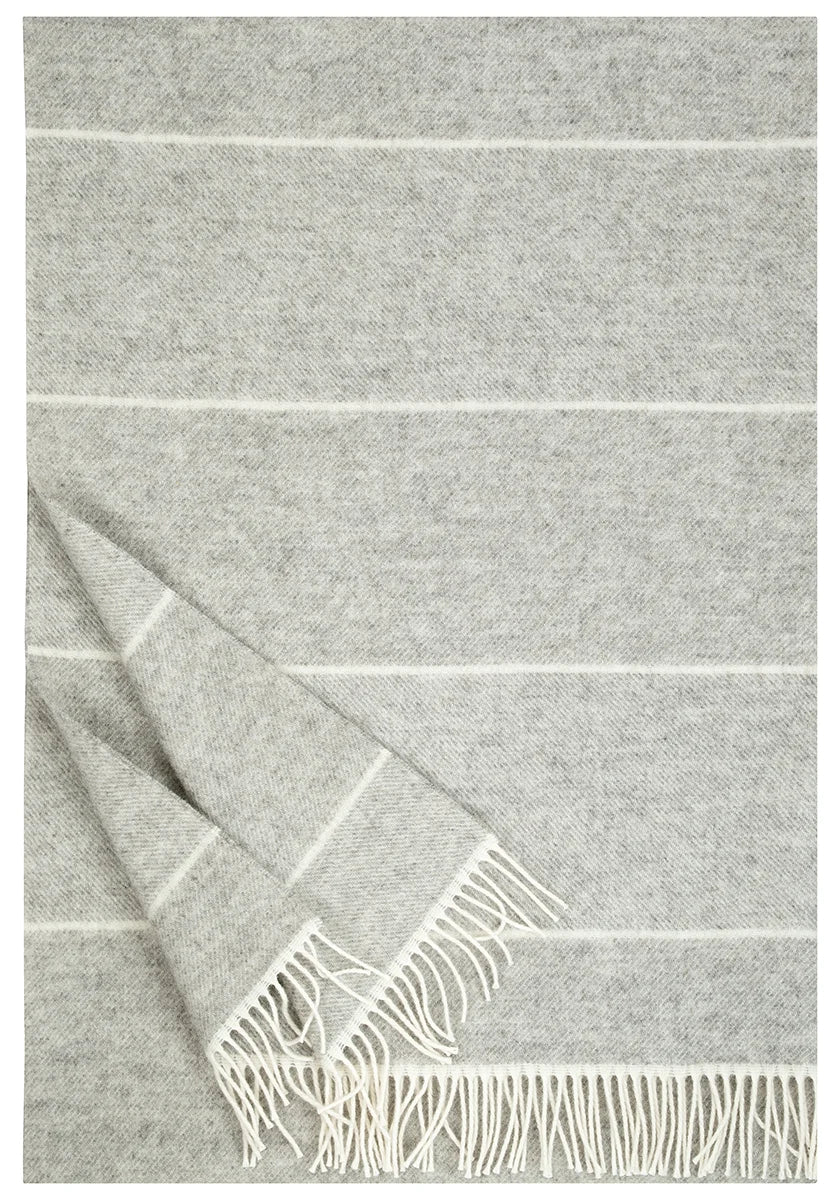 A light gray woven throw blanket with thin white horizontal stripes and fringed edges, shown folded on a white background.