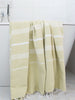 Yellow towel with white stripes draped over a bathtub in a bathroom setting.
