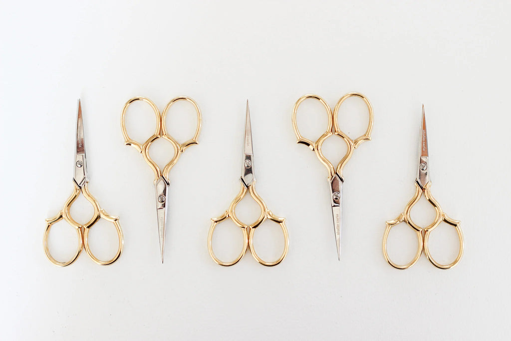 Set of five pairs of gold-handled scissors on a white background