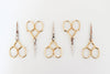 Set of five pairs of gold-handled scissors on a white background
