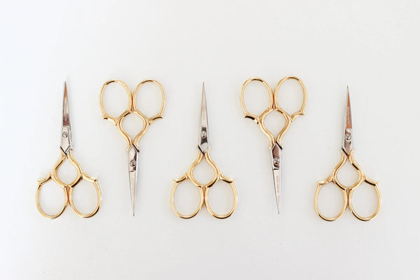 Set of five pairs of gold-handled scissors on a white background
