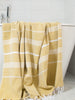Yellow towel with white stripes draped over a bathtub in a bathroom setting.