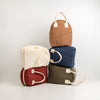 Five fabric bags in different colors stacked on a white background