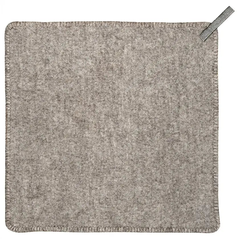 A square gray wool seat pad with fringed edges and a small gray pull tab in the top right corner, shown flat against a white background.