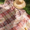 Checkered picnic blanket with a straw hat on grass
