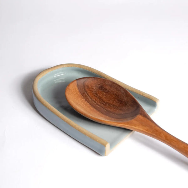 Wooden spoon on a ceramic dish with a light gray background
