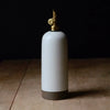 White ceramic oil bottle with gold cap on a wooden surface