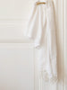 White towel with white fringes draped over a white door.